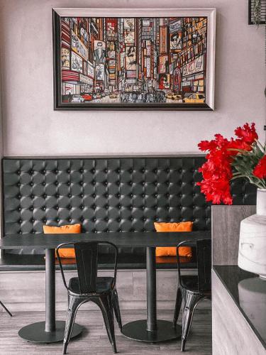 a black table with chairs and a painting on the wall at Campagne Hotel and Residence - SHA Plus in Pathum Thani