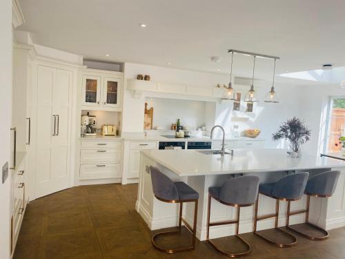 a kitchen with white cabinets and a large island with blue chairs at Guesthouse in Central Fleet in Fleet