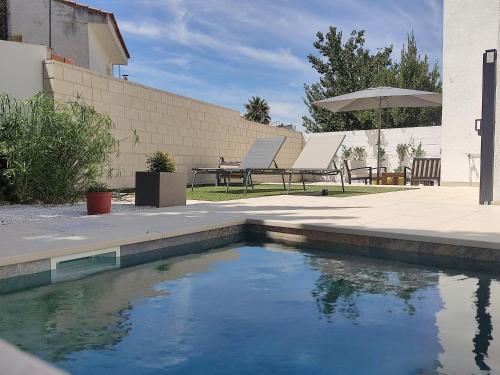 a swimming pool with two chairs and an umbrella at Apto. El Pozo de las Nieves con piscina in Cobisa
