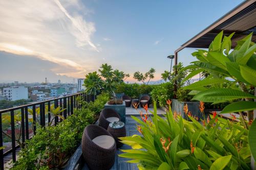 uma varanda com cadeiras e plantas num edifício em Bonny Boutique Hotel Da Nang em Da Nang