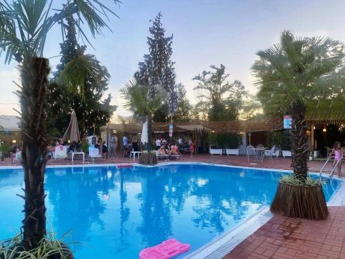 a large swimming pool with palm trees in a resort at Assembly Hotel in Anchialos