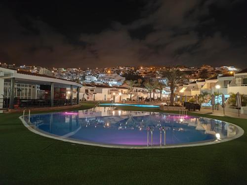 a swimming pool at night with a city in the background at Malibu Park Apartments Sol in Adeje