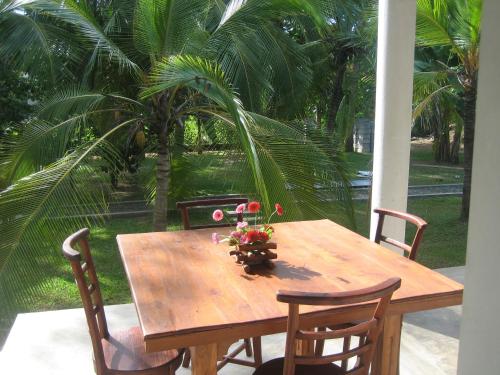a wooden table with chairs and a vase of flowers on it at Liyana Holiday resort in Anuradhapura