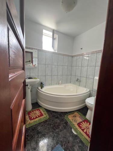 a white bathroom with a tub and a toilet at Casa Floarea de Colt in Azuga