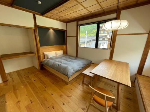 a small room with a bed and a table at Yubaba House Downtown Apartments in Nozawa Onsen