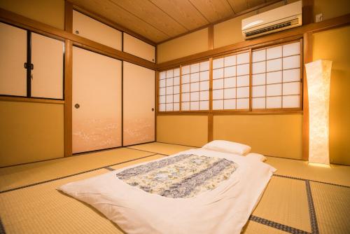 a bedroom with a bed in a room with windows at 喜楽・里桜 in Kyoto
