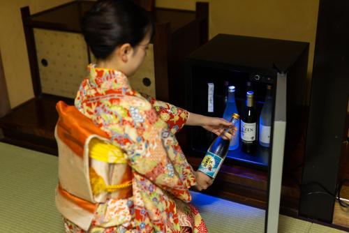 una mujer en un kimono sosteniendo una botella de vino en ‐izen 高田‐ 楽酔亭, en Joetsu