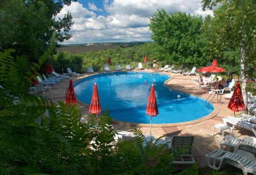 uma grande piscina com guarda-sóis, cadeiras e mesas em Rilena Hotel em Kiten