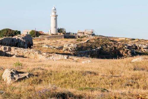 a lighthouse on top of a hill with a field at Mayfair Gardens in Paphos City