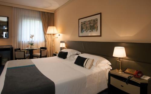 una camera d'albergo con un grande letto e un tavolo di Park Hotel Ai Cappuccini a Gubbio