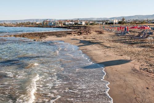 a sandy beach with chairs and the ocean at Mayfair Gardens in Paphos City