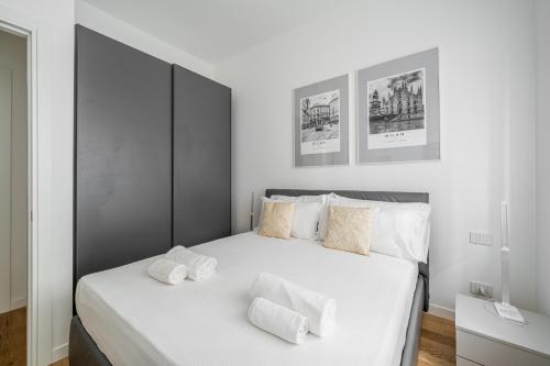 a white bedroom with a large bed with white pillows at Easylife - Moderno rifugio a due passi dal duomo in Milan