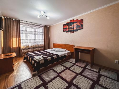 1 dormitorio con cama, mesa y ventana en Тасс уютная квартира в центре города, en Petropavlovsk