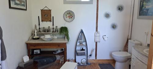 La salle de bains est pourvue d'un lavabo, de toilettes et d'une planche de surf murale. dans l'établissement Le Soleil Levant, à Saint-Gatien-des-Bois
