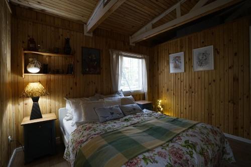 1 dormitorio con cama, lámpara y ventana en Sosnowy Zakątek - domek wakacyjny nad jeziorem w lesie en Tuczno