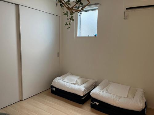 Cette chambre comprend 2 lits et une fenêtre. dans l'établissement trive osu east 駅チカ 大須観音通商店街スグ, à Nagoya