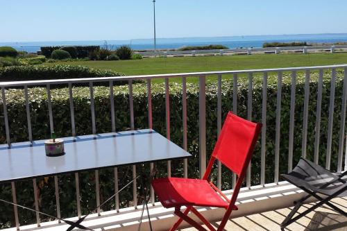 a red chair sitting next to a table on a balcony at Appartement Belles Vacances in Quiberon