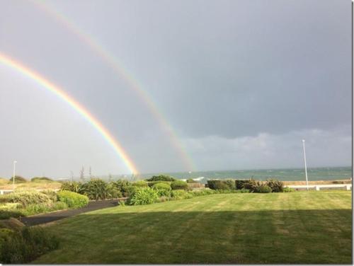a rainbow in the sky over a field at Appartement Belles Vacances in Quiberon