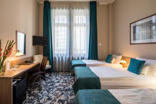 a hotel room with two beds and a desk at Erzsébet Királyné Szálloda in Gödöllő