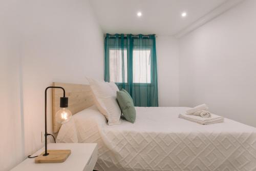 a white bedroom with a bed and a lamp at Apartamento MARCO a 250m playa in Calpe