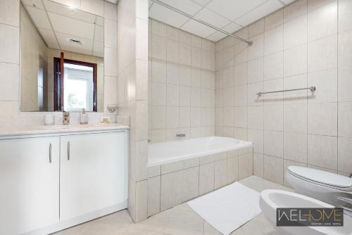WelHome - Prime Apartment With Balcony Amidst Lively Area في دبي: حمام أبيض مع حوض ومرحاض