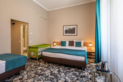 a hotel room with a bed with blue sheets at Erzsébet Királyné Szálloda in Gödöllő