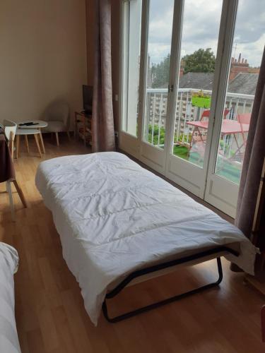 un lit dans une chambre avec une grande fenêtre dans l'établissement L'échappée blésoise, à Blois