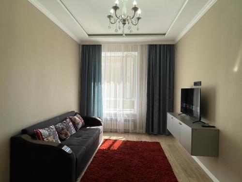 Una sala de estar con un sofá y un televisor. en Dream City 15, en Astana