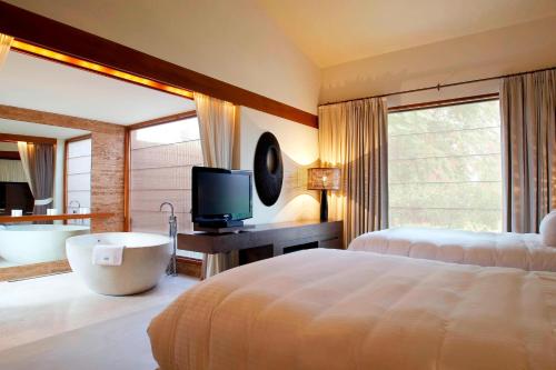 a bedroom with a bed and a tub and a television at The Westin Sohna Resort & Spa in Gurgaon