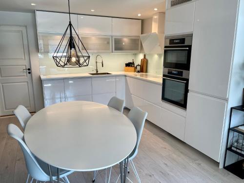 una cucina bianca con tavolo e sedie bianchi di Luxury apartement close to city centre with free parking a Tromsø