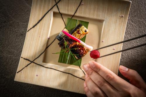 a person eating a plate of food with chopsticks at Art Hotel Narita in Narita