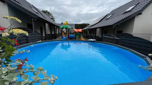 a large blue swimming pool next to a house at Domki Błażejewo in Łukęcin