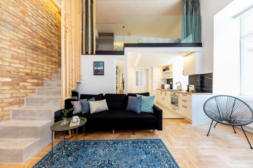 a living room with a black couch and a brick wall at KIRÁLY DOWNTOWN APARTMENT in Budapest