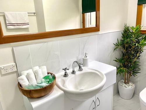 La salle de bains blanche est pourvue d'un lavabo et d'un miroir. dans l'établissement Sunny, Spacious mountain views, Holiday home, à Lenah Valley