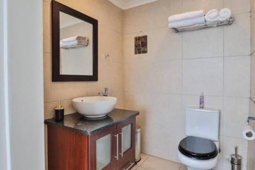 a bathroom with a sink and a toilet and a mirror at Nautical views in Mossel Bay