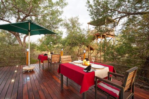 a wooden deck with two tables and a green umbrella at Moya Safari Villa in Hoedspruit