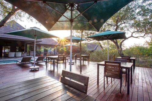 a wooden deck with tables and chairs and umbrellas at Moya Safari Villa in Hoedspruit