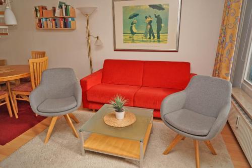 een woonkamer met een rode bank en 2 stoelen bij Penthousewohnung vor der Promenade in Damp