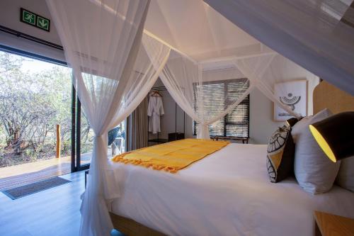 a bedroom with a canopy bed with a large window at Moya Safari Villa in Hoedspruit