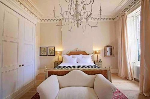a bedroom with a bed with a couch and a chandelier at Home of Joy - 3 bedroom home with private garden in Glasgow