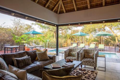 an outdoor patio with couches and chairs and a pool at Moya Safari Villa in Hoedspruit