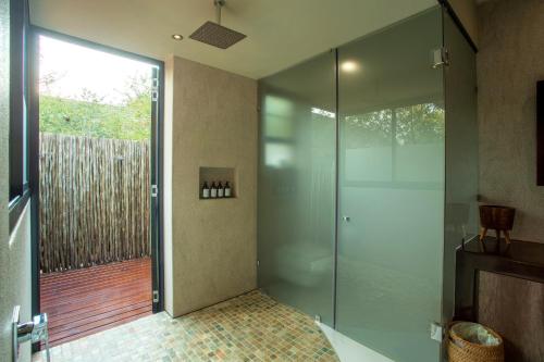 a bathroom with a shower and a glass door at Moya Safari Villa in Hoedspruit