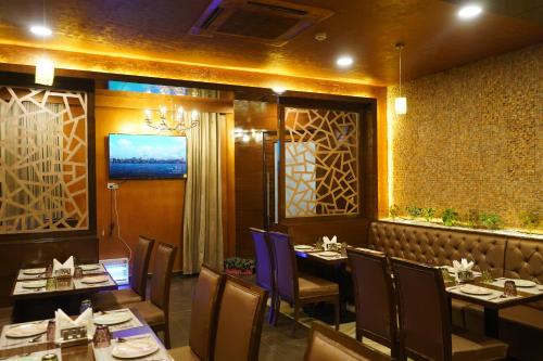 a dining room with tables and chairs and a television at THE KALINGA INN in Rohtak