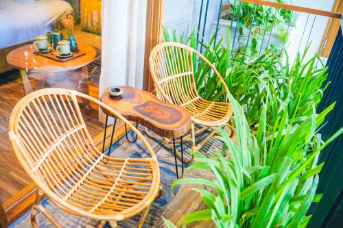 three chairs and a table in a room with plants at Bonny Boutique Hotel Da Nang in Da Nang