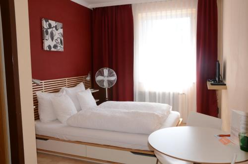 a bedroom with a bed with red walls and a window at HOTEL MARIA in Gramatneusiedl