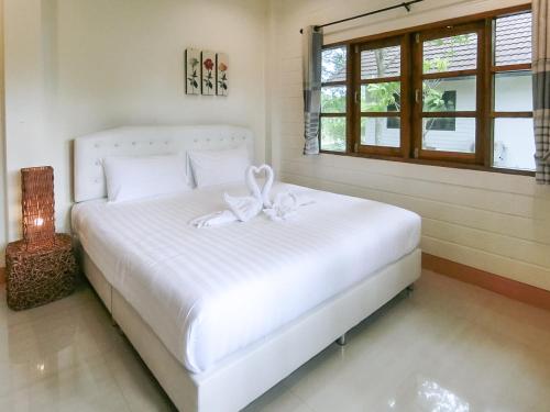 a bedroom with a white bed with a bow on it at AURA Park Resort in Ban Thung Sam Sao