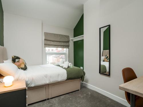 a bedroom with green walls and a bed with a mirror at Pass the Keys Stylish Aigburth Flat Sleeps 12 in Liverpool