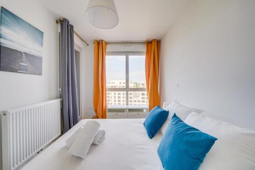 um quarto com uma cama com almofadas azuis e uma janela em Les Hauts St Louis - Appt avec terrasse em Bordeaux