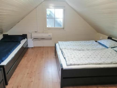 a attic bedroom with two beds and a window at Počitniška hišica Patrik in Mostec