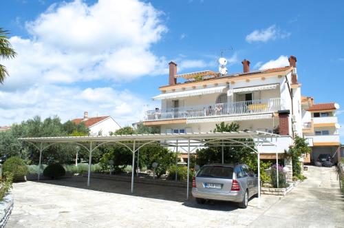 a car parked in a parking lot in front of a building at Pansion Adria in Sveti Filip i Jakov